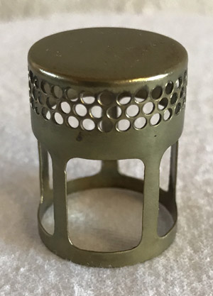 Small cylindrical metal object with perforated circular holes near the top and large rectangular cutouts below.