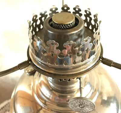 Close-up of a vintage brass kerosene lantern burner with adjustable knob and flame protector.