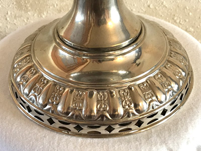 Close-up of a detailed silver base with floral and geometric cut-out designs.