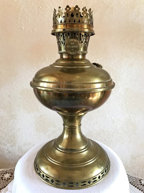 Antique brass oil lamp with decorative crown-shaped burner on a round base.