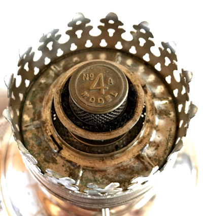 Close-up top view of an antique No 4 Model A metal oil lamp burner with a decorative crown.