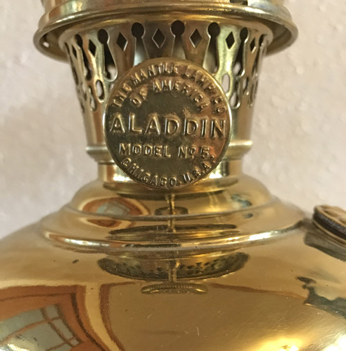 Close-up of a brass Aladdin Model No 5 lamp burner with embossed text and decorative holes.