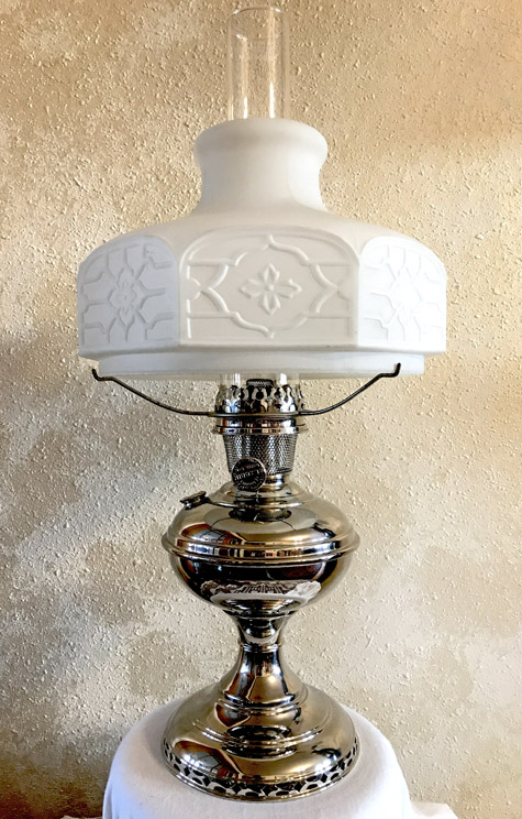 Vintage silver metal oil lamp with white frosted glass shade featuring geometric floral patterns.