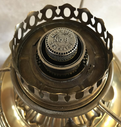 Close-up of a vintage brass Paladin No. 8 generator on an antique oil lamp.