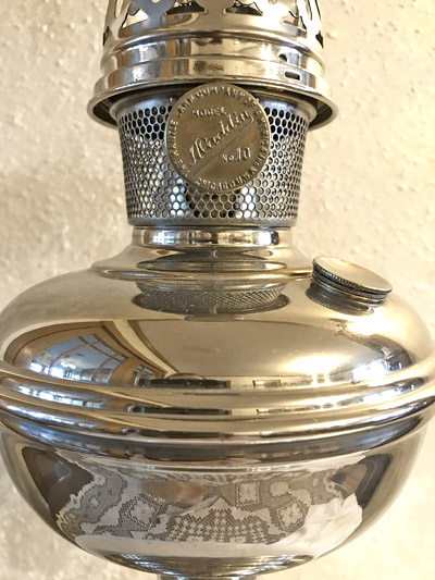 Close-up of a shiny metal lantern with a vented collar marked 'Made in England, No. 10'.