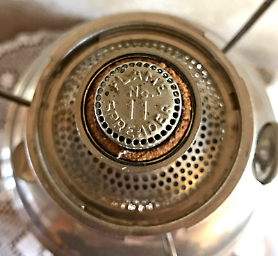 Close-up top view of an antique vaporizer or stove burner with perforated metal and Ventamatic No. 11 label.