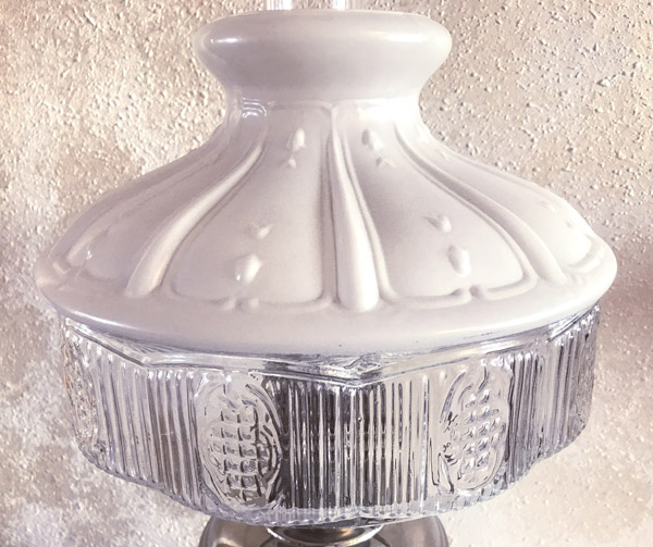 Vintage lamp with a decorative white upper shade and a clear glass lower shade with patterns.