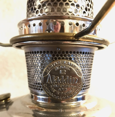 Close-up of a metal Aladdin Model 12 lamp burner with perforated design and branding plaque.
