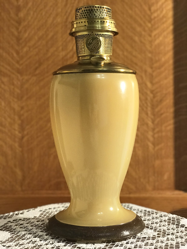 Vintage pale yellow decorative lamp with brass top on lace cloth and wooden background.