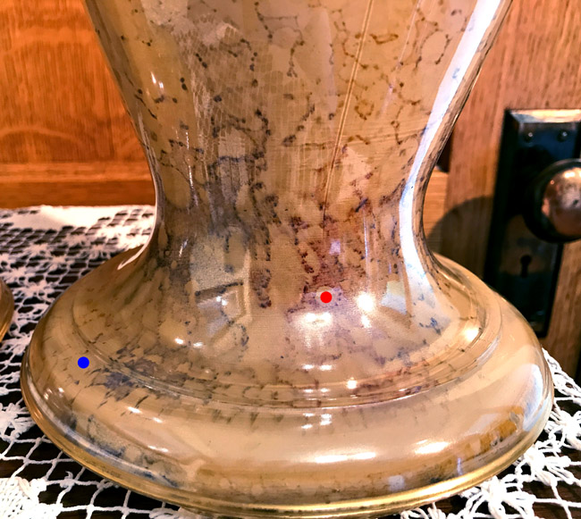Close-up of a peach-colored ceramic vase with a crackled glaze finish on a lace tablecloth.