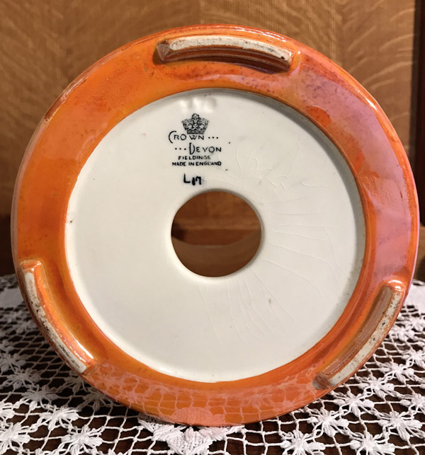 Bottom of an orange ceramic item with a hole in the center and Crown Devon England mark.