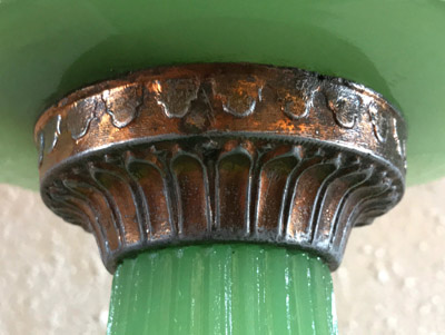 Close-up of a decorative metal connector attaching a green glass or jade part to another section.