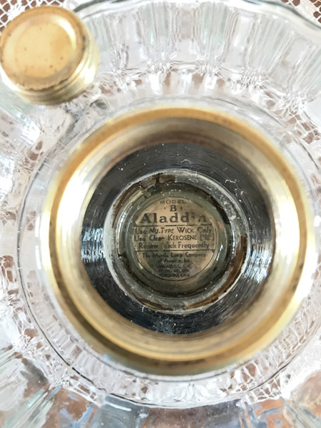 Close-up of the inside of a vintage Aladdin kerosene lamp with label visible at the bottom.