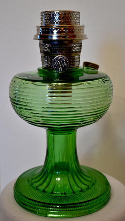 Green vintage glass oil lamp with ribbed design and metal burner on top.