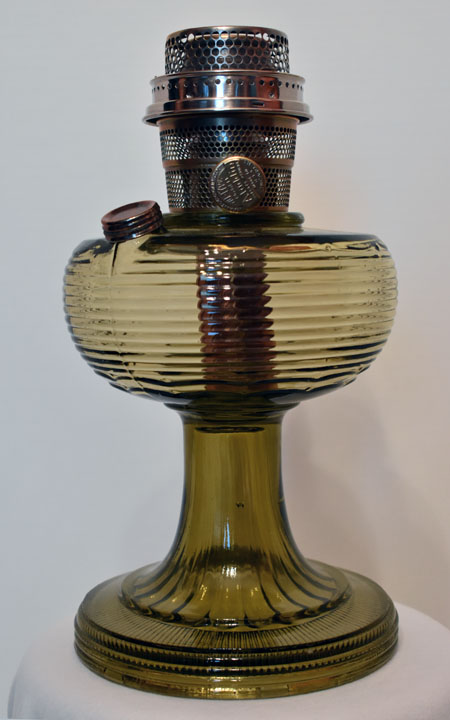 Vintage green glass oil lamp with metal burner and wick adjustment knob.