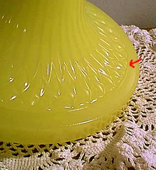 Close-up of a yellow glass plate with decorative patterns on a crocheted lace surface.