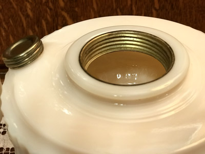Close-up of the threaded opening and detached metal cap of a white ceramic container.