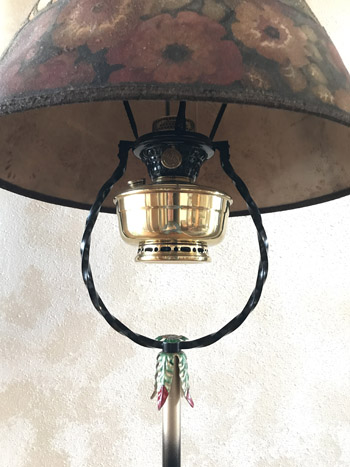 Close-up of vintage brass lamp burner with a floral-patterned lampshade above it.