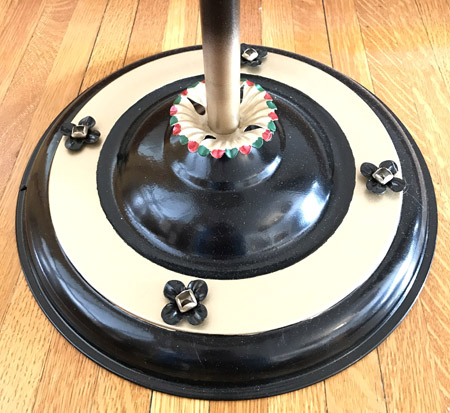 Round black and beige lamp base with four black flower-shaped decorations on wooden floor.
