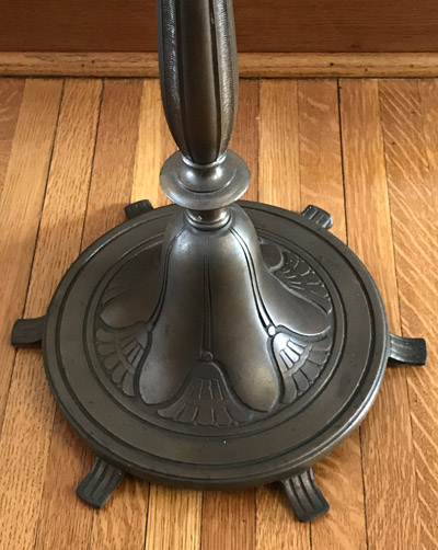 Decorative metal base of a lamp or stand on a wooden floor.