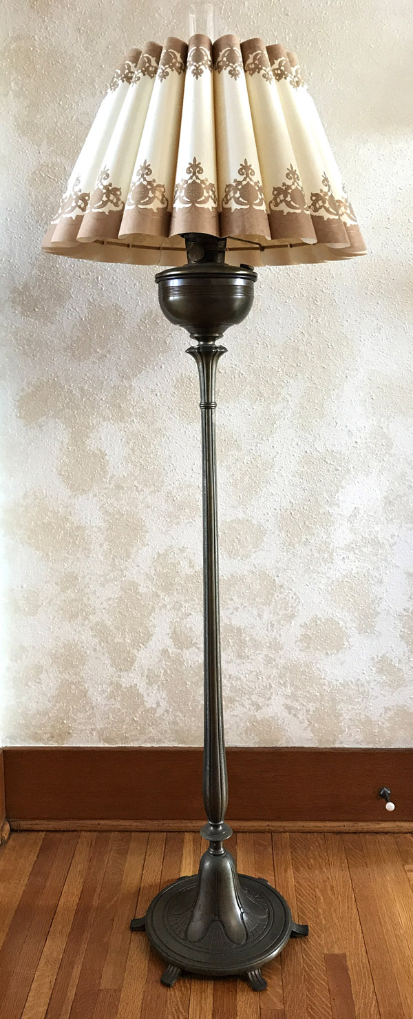 Tall vintage floor lamp with ornate metal base and pleated cream and brown patterned lampshade.