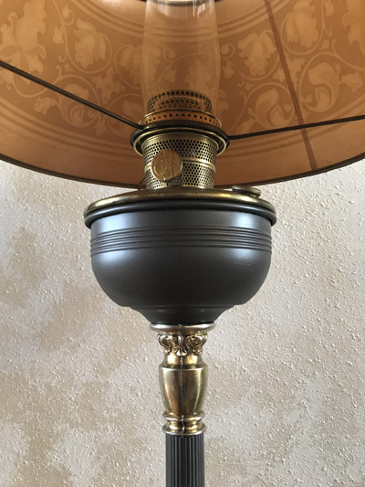 Close-up of a vintage Aladdin-style oil lamp with a glass chimney and ornate brass details.