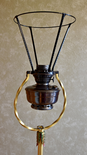 Vintage-style metal lamp frame with a round holder and gold ribbon detail on beige background.