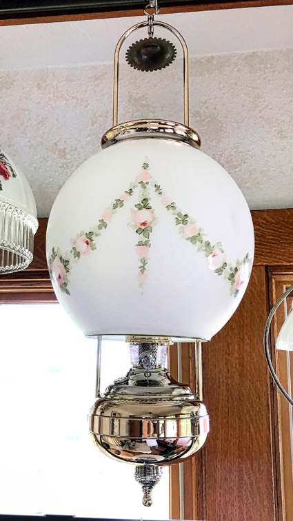Vintage hanging lamp with white floral globe and polished brass metal parts.