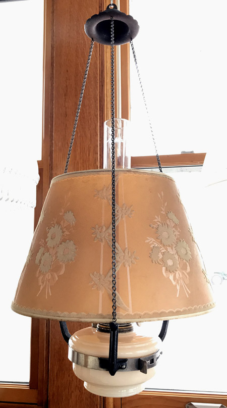Vintage hanging lamp with floral-patterned beige shade suspended by black chains.