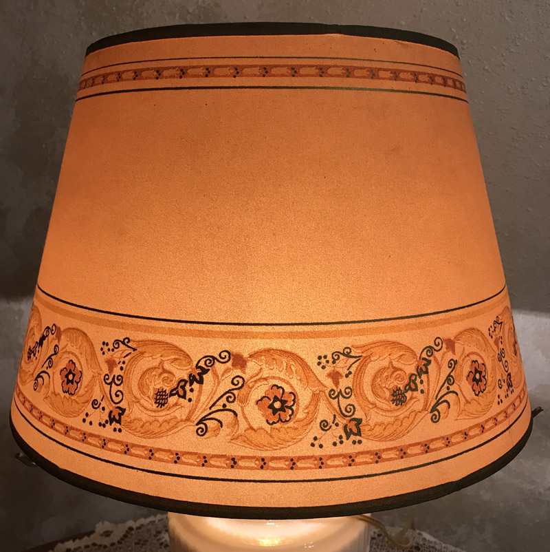 Orange lampshade with floral and swirl patterns bordered by thin black lines.