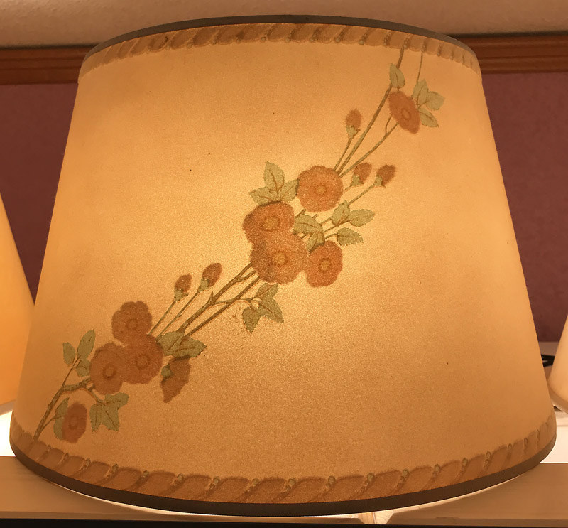 Brown lampshade with a floral design featuring orange flowers and green leaves in a diagonal pattern.