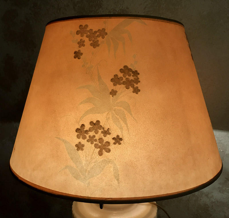 Orange lampshade with brown floral patterns and a subtle leaf design, lit from inside.