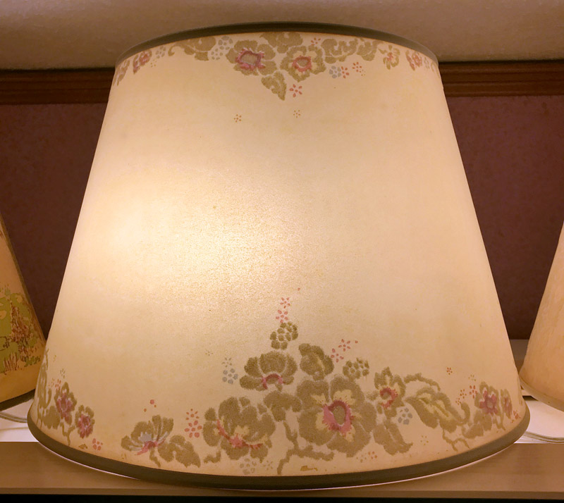 Beige lampshade with floral pattern in muted green and pink tones on top and bottom edges.
