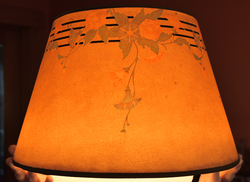 Orange lampshade with a floral vine pattern and black horizontal stripes near the top edge.