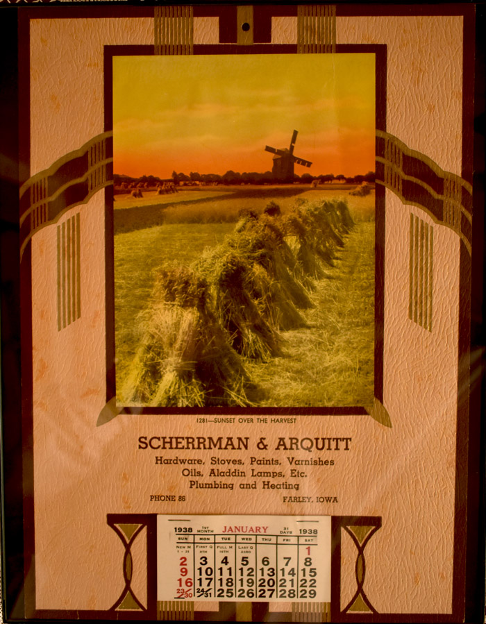 1938 calendar page with a sunset harvest photo featuring a windmill and haystacks in a field.