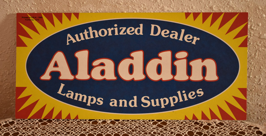 Sign reading 'Authorized Dealer Aladdin Lamps and Supplies' with a yellow and red sunburst border.