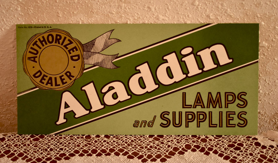 Vintage sign reading Authorized Dealer Aladdin Lamps and Supplies on a green background.