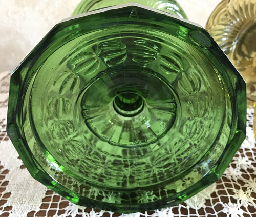Top view of a green glass bowl with textured circular patterns on a lace tablecloth.