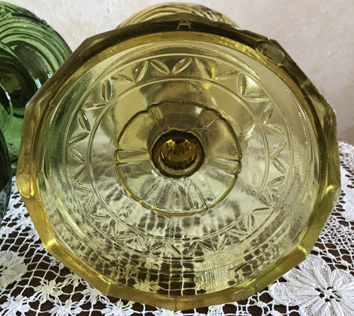 Close-up of a yellow glass object with a floral embossed pattern on a white lace cloth.