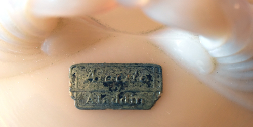 Close-up of a small rectangular metal tag with the text 'Made for Avalons' on a beige surface.