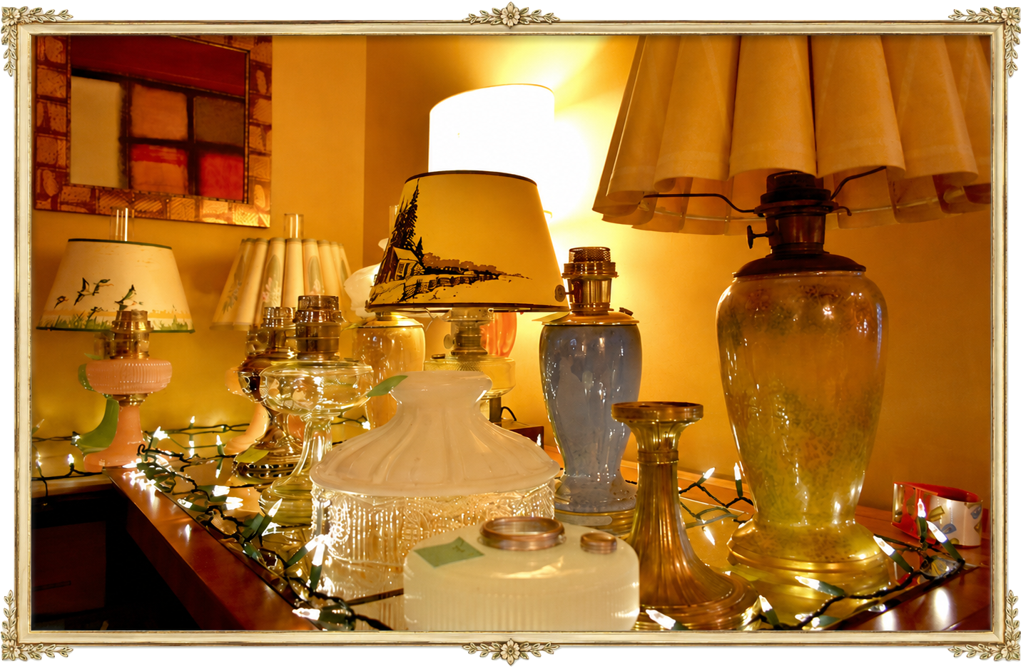 Collection of vintage oil lamps and lamp shades on a wooden surface with string lights.