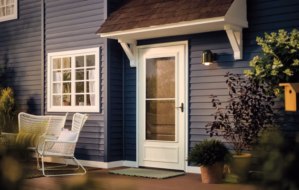 White fiberglass patio door with screen on a blue house, flanked by potted plants and outdoor seating.