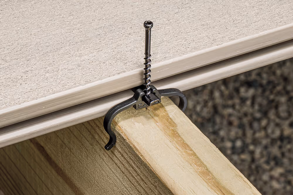 Close-up of a black hidden fastener securing a screw through a beige composite deck board onto a wooden joist.