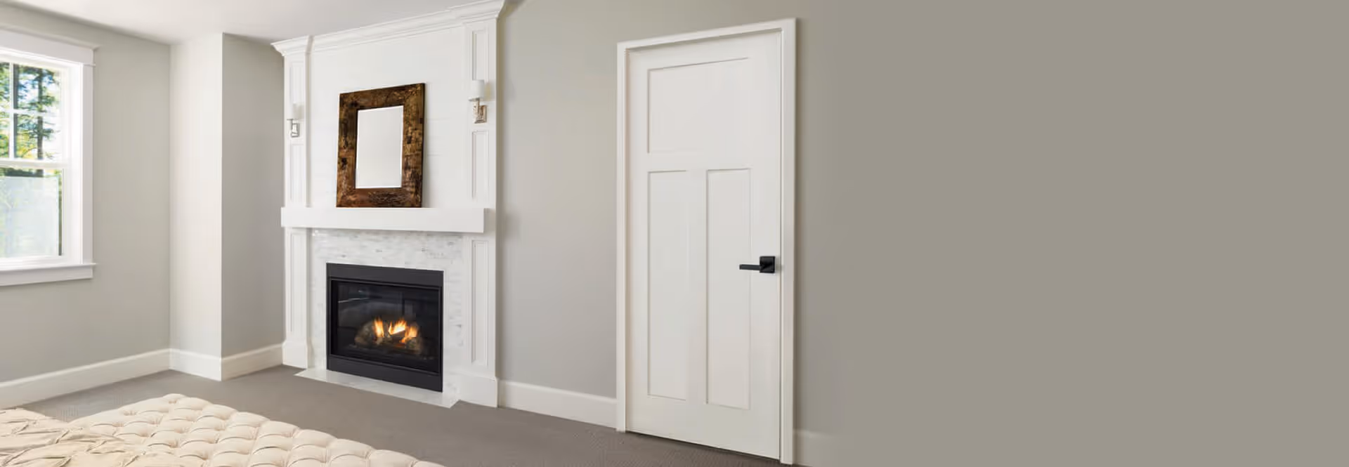 Bright room with a white paneled door, a lit fireplace with a decorative mantel, and a window letting in natural light.