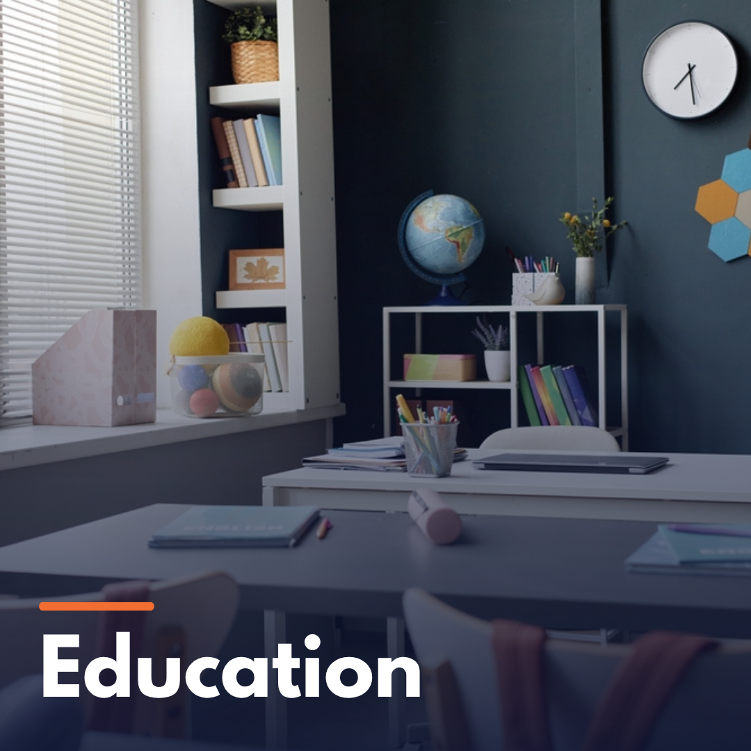 Classroom interior with desks, chairs, globe, books, and stationery on a dark blue wall background.