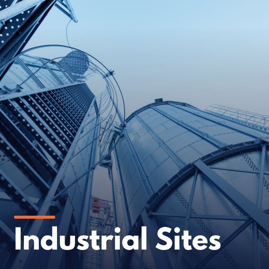 Upward view of metal industrial storage tanks and a safety ladder structure with clear sky background.