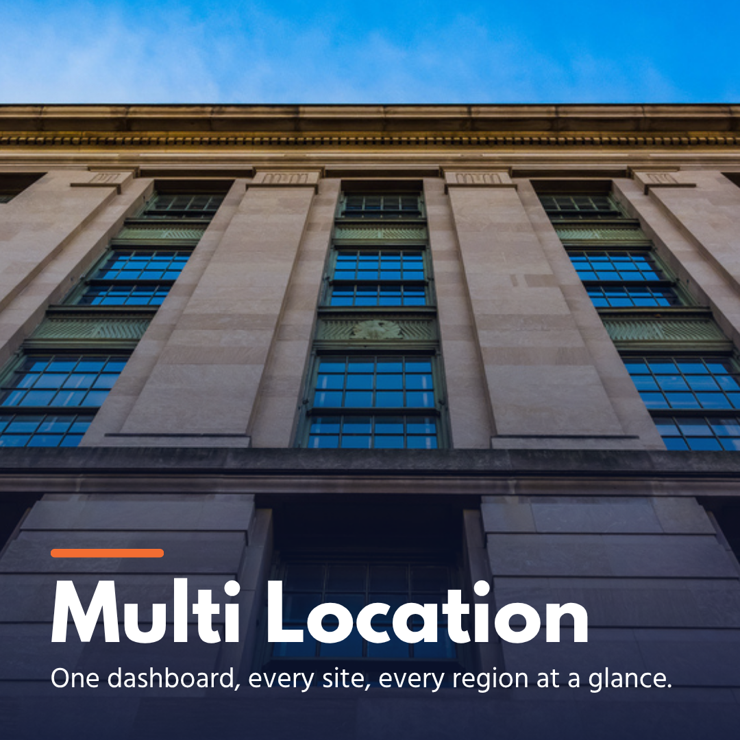 Facade of a tall office building with multiple large windows under a clear blue sky.