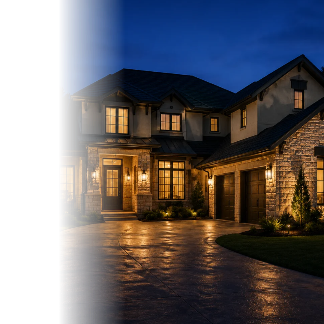 Modern two-story house at night with exterior lights on and wet driveway reflecting light.