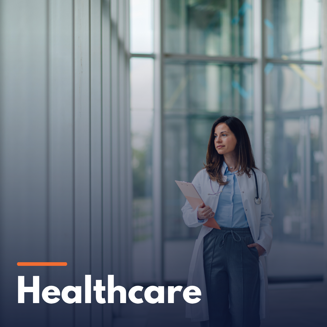 Female doctor in white coat holding clipboard standing in a modern glass hospital corridor.