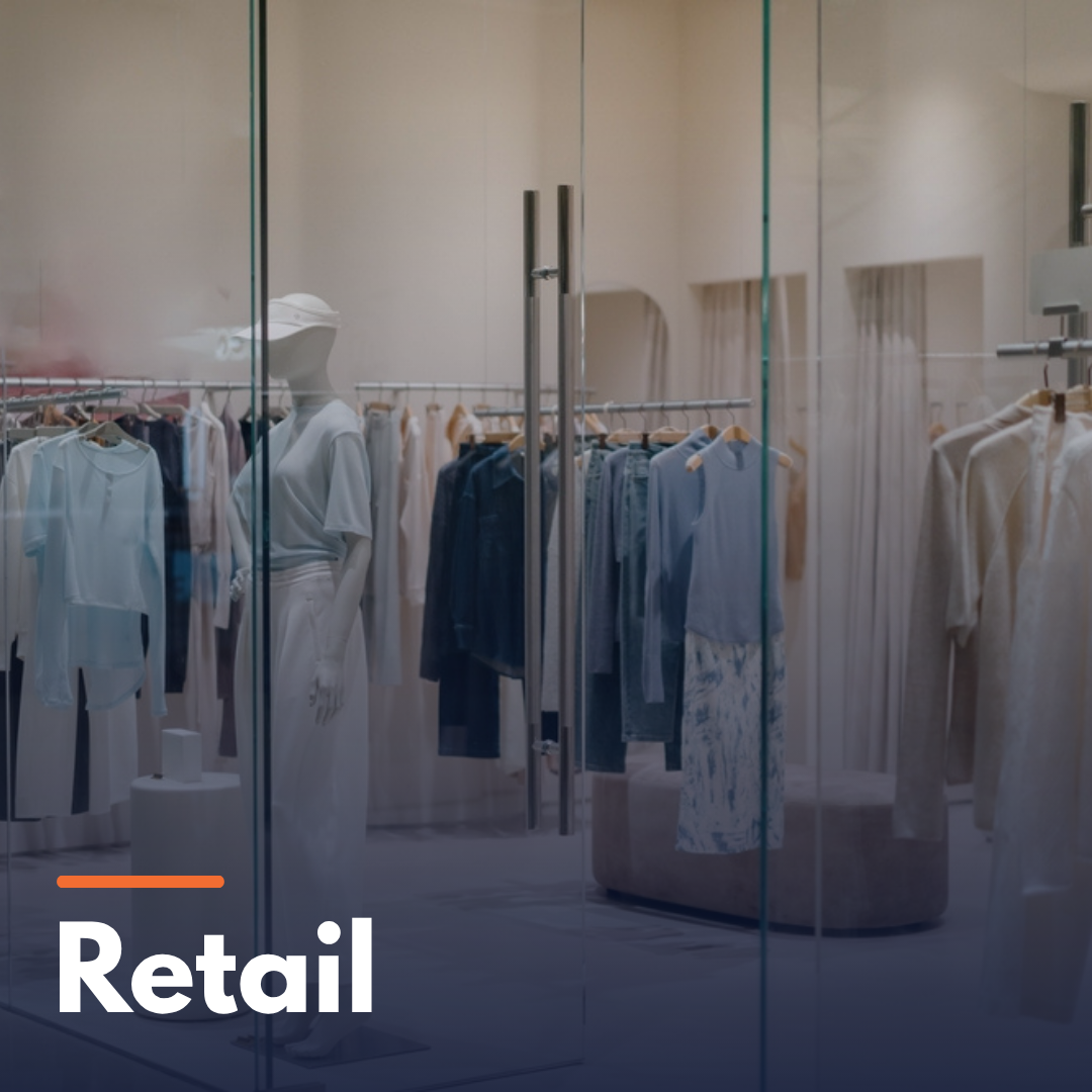 Clothing store interior with mannequin and garments hanging on racks behind glass doors.